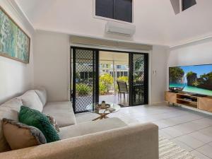 a living room with a couch and a tv at Canopy Chalet 10 in Nelly Bay