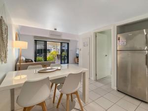 a kitchen and dining room with a white table and chairs at Canopy Chalet 10 in Nelly Bay +2 photos