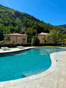 a swimming pool with blue water in front of a house at Hotel Catalunya Park in Ribes de Freser