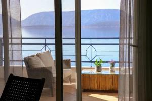 a room with a balcony with a view of the water at Grand Bleu Apartments & Villas in Ermioni