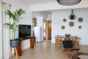 a living room with a television and a table with a plant at Grand Bleu Apartments & Villas in Ermioni