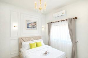 a white bedroom with a bed and a chandelier at Chill Sbai Villa Pattaya in Nong Prue