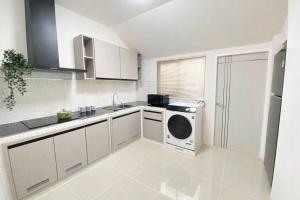 a white kitchen with a washing machine in it at Chill Sbai Villa Pattaya in Nong Prue