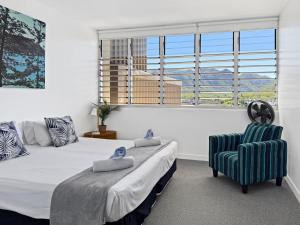 a bedroom with a bed and a chair and a window at 1 Bright Point Apartment 4501 in Nelly Bay