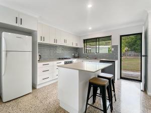 a kitchen with white cabinets and a white refrigerator at Nerita Nook in Nelly Bay