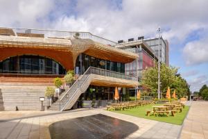 a building with tables and chairs in front of it at Holiday Inn Express London Stratford by IHG in London