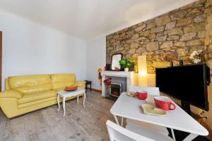 a living room with a yellow couch and a stone wall at Appartement centre de Crozon in Crozon