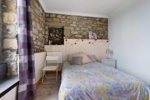 a bedroom with a bed and a stone wall at Appartement centre de Crozon in Crozon