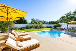a pool with lounge chairs and a yellow umbrella at Duck Resort with Ocean Views Pool HotTub Elevator in Kitty Hawk Beach