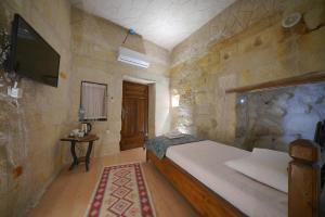 a bedroom with a bed and a tv on a wall at Coco Cave in Göreme