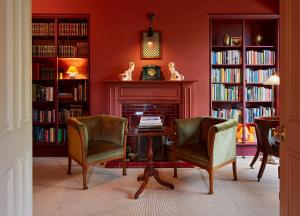 a library with two chairs and a table and a fireplace at Penmaenuchaf Hotel in Dolgellau
