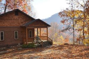 a log cabin with a porch and stairs in the woods at Millstone Lodge Cabin in Bryson City