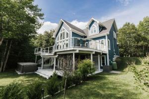 a large blue house with a large yard at Luxurious Lakeside Chalet with Swim Spa in South Brook