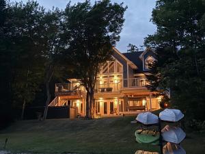 a large house with a tree in the yard at Luxurious Lakeside Chalet with Swim Spa in South Brook