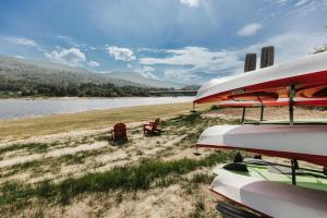 a person sitting on a beach next to a body of water at Luxurious Lakeside Chalet with Swim Spa in South Brook +28 photos