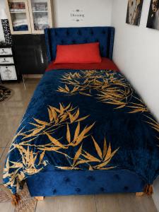 a bed with a blue comforter and a red pillow at L'océane in Saint-Maurice-de-Beynost