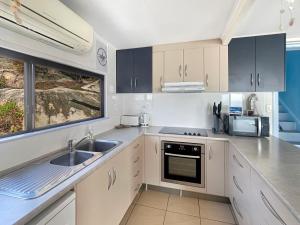 a kitchen with white cabinets and a sink and a window at Blue on Cockle in Picnic Bay
