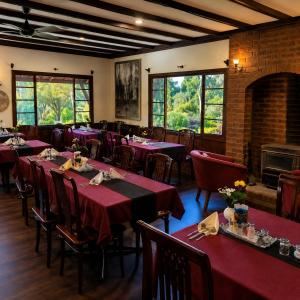 a restaurant with red tables and chairs and a fireplace at Karri Forest Motel in Pemberton