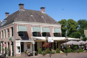 a building with tables and umbrellas on a street at Geinig Amsterdam in Abcoude