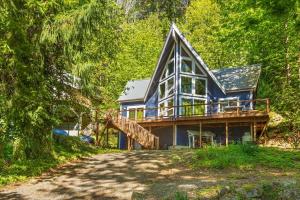 a blue house with a deck in the woods at A-Frame Cabin Dock Access & Views BBQ in Hoodsport
