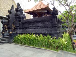 a black building with a roof and some plants at G'Sign Style Hotel in Kuta
