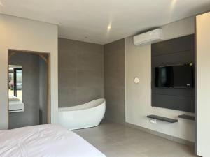 a bedroom with a tub and a tv and a bed at Lehumo Guesthouse in Mogales