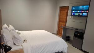 a bedroom with a white bed and a flat screen tv at Lehumo Guesthouse in Mogales