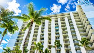 a tall white building with palm trees in front of it at Hawaiian Princess Beachfront 1BR in Waianae