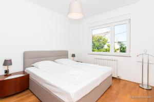 a white bedroom with a bed and a window at Residence Almarea by Locap Group in Izola