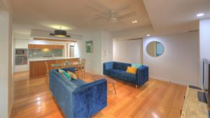 a living room with two blue couches and a kitchen at Maggies Beachfront Apartment 4 in Horseshoe Bay +14 photos