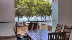 a table and chairs on a balcony with a view of the beach at Maggies Beachfront Apartment 4 in Horseshoe Bay