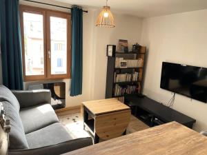 a living room with a couch and a tv at Appartement cocooning centre ville in Embrun