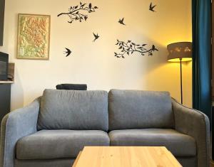 a living room with a couch and birds on the wall at Appartement cocooning centre ville in Embrun