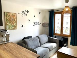 a living room with a couch and birds on the wall at Appartement cocooning centre ville in Embrun