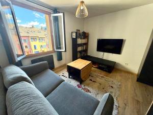 a living room with a couch and a flat screen tv at Appartement cocooning centre ville in Embrun