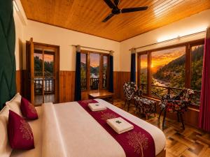 a bedroom with a bed and a balcony with a view at Sneha Riverside Cottage, Tirthan Valley - Best selling cottage in Jibhi 2025-26 in Jibhi