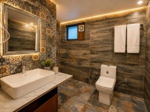a bathroom with a sink and a toilet and a mirror at Sneha Riverside Cottage, Tirthan Valley - Best selling cottage in Jibhi 2025-26 in Jibhi