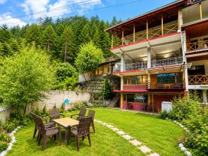 a house with a table and chairs in the yard at Sneha Riverside Cottage, Tirthan Valley - Best selling cottage in Jibhi 2025-26 in Jibhi