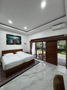 a bedroom with a bed and a sliding glass door at Casa De Brillo Tegallalang in Tegalalang