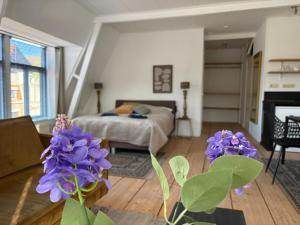 a bedroom with a bed and purple flowers in a room at Logement Hoogend in Sneek
