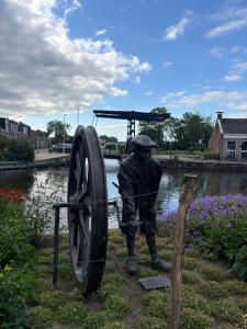 a statue of a man standing next to a large wheel at Logement Hoogend in Sneek