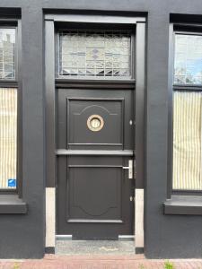 a black door on a building with two windows at Logement Hoogend in Sneek +4 photos