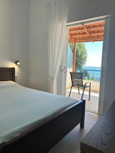 a bedroom with a bed and a chair and a patio at Paliovarka Rooms in Mitika