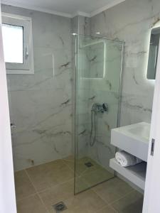 a bathroom with a glass shower and a sink at Paliovarka Rooms in Mitika