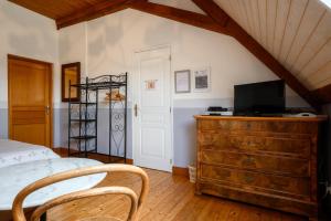 a bedroom with a bed and a tv on a dresser at Chambres d'hôtes, Les Combes in Orbey
