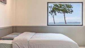 a bed in a room with a window at Mu-an Prejong Dokchae Pension in Muan