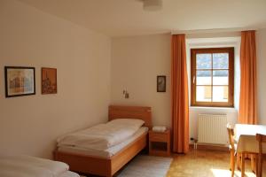 a bedroom with two beds and a table and a window at Benediktinerstift Michaelbeuern in Michaelbeuern