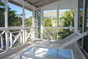 a white rocking chair on a porch with windows at Oualie Beach Resort in Nevis