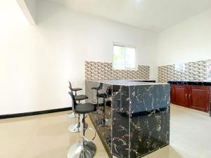 a kitchen with a counter and two stools in a room at Urbanview Bangsal Mojokerto in Ngranggon