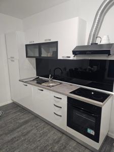 a white kitchen with a stove and a sink at Apartman Rena in Ivanec